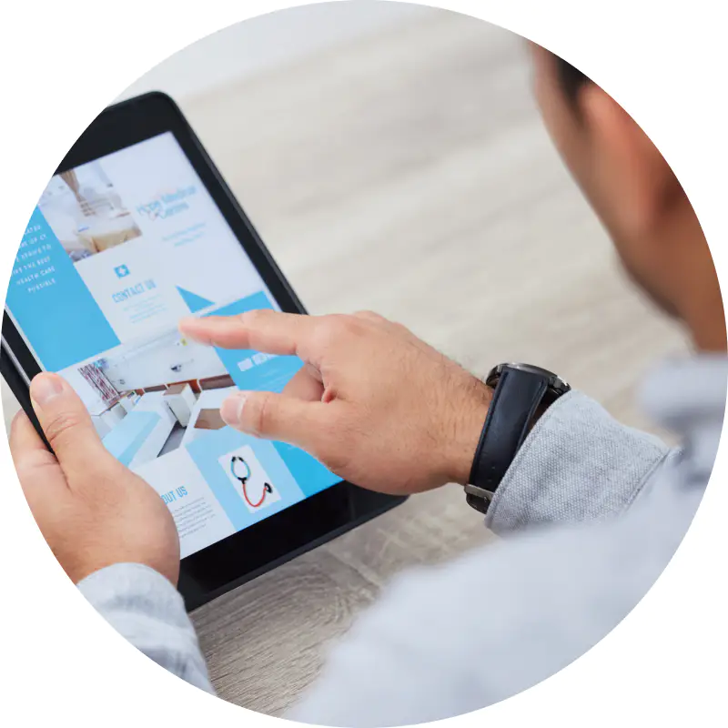 Eine Person benutzt ein Tablet und durchsucht eine Website mit Bildern und Text, als würde sie durch digitale Seiten blättern. Sie zeigt auf den Bildschirm, trägt ein graues Langarmshirt und eine schwarze Uhr. Die Szene ist in einem kreisförmigen Rahmen dargestellt.