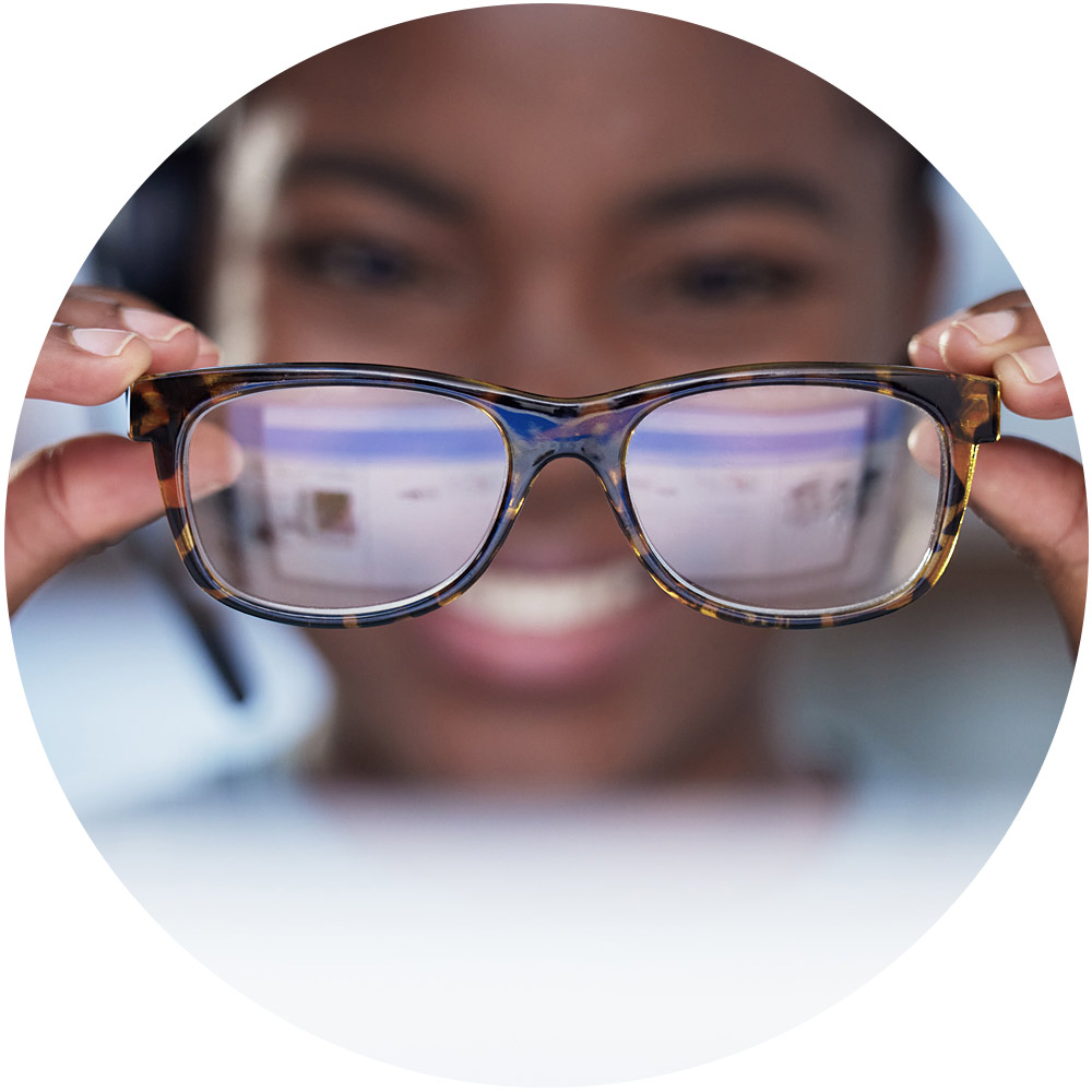 Eine Person lächelt und hält eine Schildpattbrille vor ihr Gesicht, deren Gläser einen verschwommenen Bildschirm reflektieren, was an ansprechende Microsites erinnert. Das Bild ist elegant in einen kreisförmigen Rahmen eingebettet.