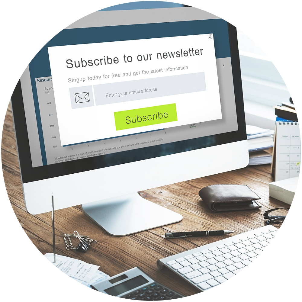 Auf einem Computerbildschirm ist ein Popup-Formular für die Newsletter-Anmeldung mit Feldern für die E-Mail-Eingabe und einem grünen „Abonnieren“-Button zu sehen. Auf dem Schreibtisch stehen eine Tastatur, eine Maus, eine Brille, ein Stift und ein Buch. Wenn das Sonnenlicht durch das Fenster fällt, wirkt die einladende Einrichtung fast wie eine Szene aus Ihrem Lieblingsvideo.